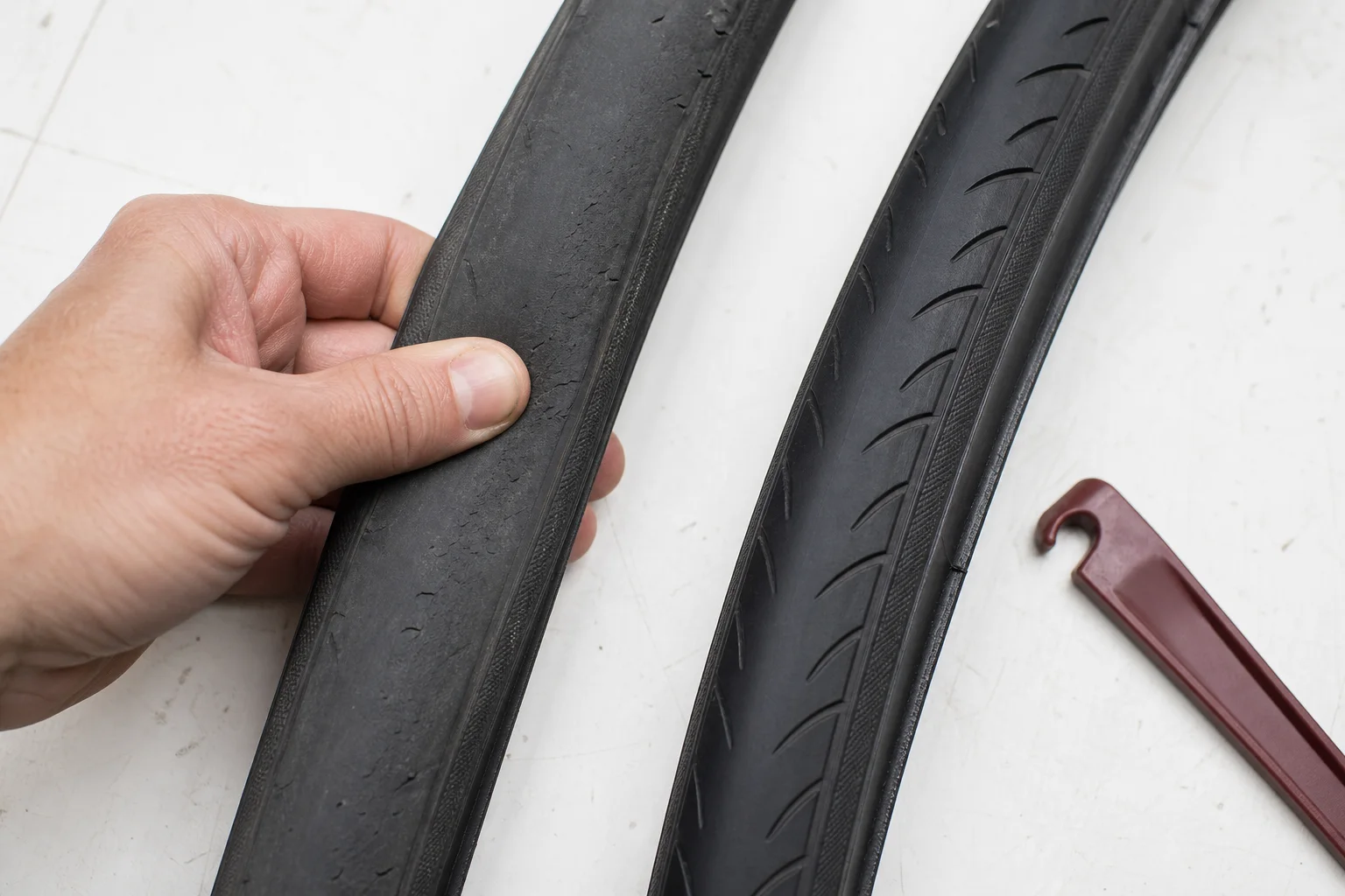 A flattened worn bicycle tire beside a newer tire with healthy tread